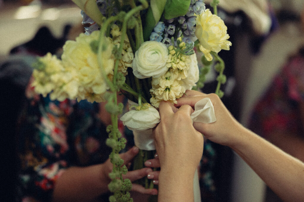 documentary style wedding photos a pair of hands ties a bow around a handmade bouquet