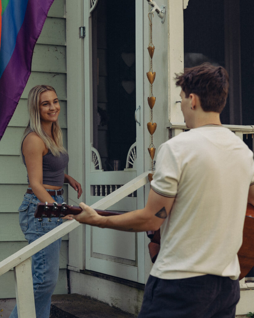 a man plays a guitar serenading his fiancee during their engagement photos at home