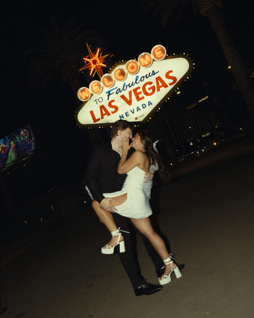 newlyweds lean in for a smiling kiss for their vegas elopement phiotography under the las vegas lights