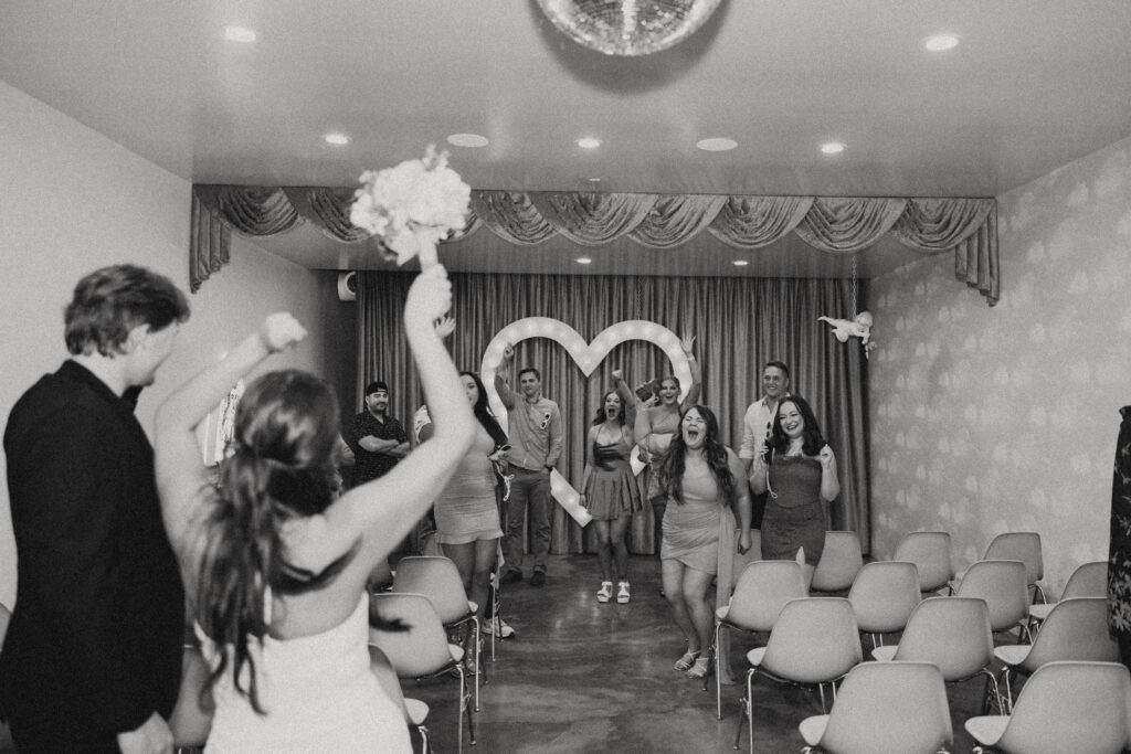 wedding photos in vegas where the couple stand in the foreground with their arms in the air while their friends cheer in the background