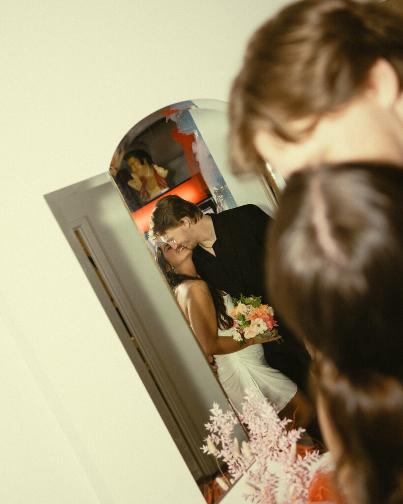 newlyweds share a kiss in front of a mirror
