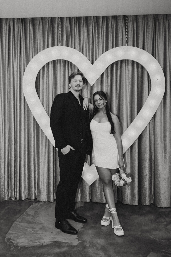 wedding photos in vegas where the newlyweds stand in front of a heart shaped sign at the chapel