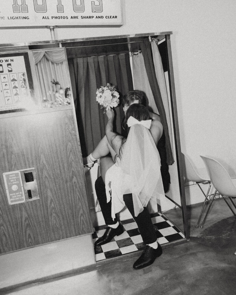 newlyweds sit together in a photobooth showing us her bow and veil during their wedding photos in vegas