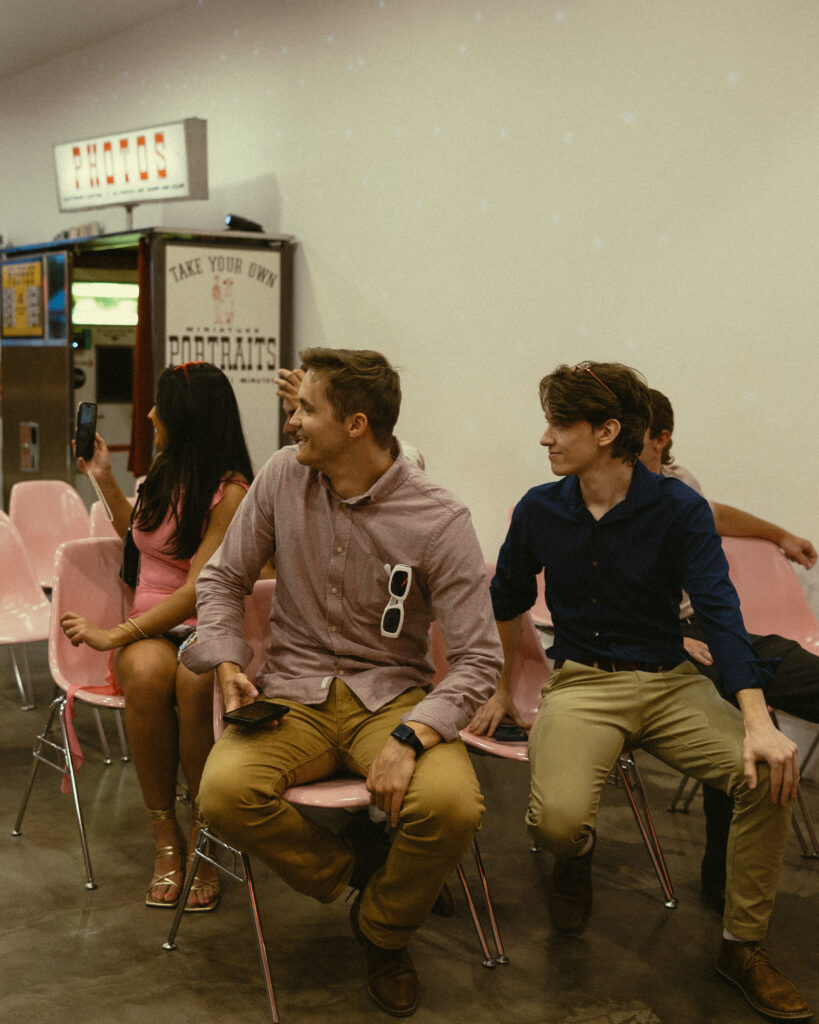 friends of the bride and groom look excitedly back in their seats as the bride walks down the aisle during the ceremony