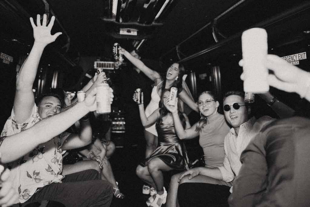 a bride and her friends raise their cans and smile during a vegas elopement photography on a partybus