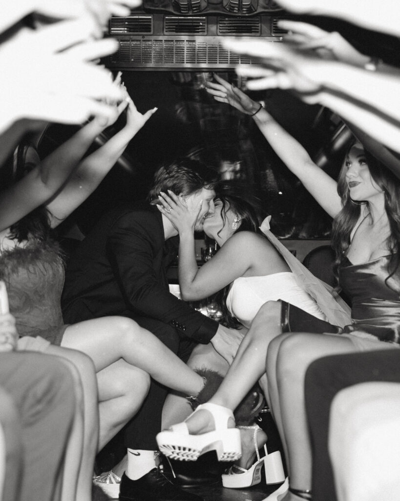 newlyweds share a kiss for their wedding photos in vegas surrounded by their friends on a party bus