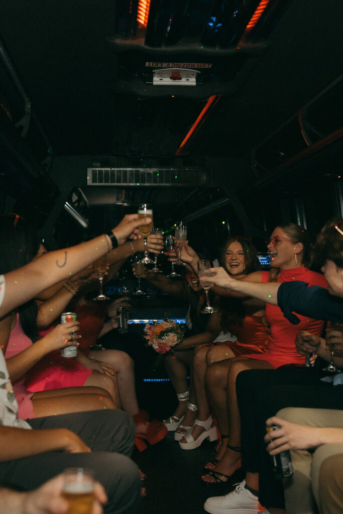 a group of people smile and laugh while raising their glasses to cheers while riding on a party bus