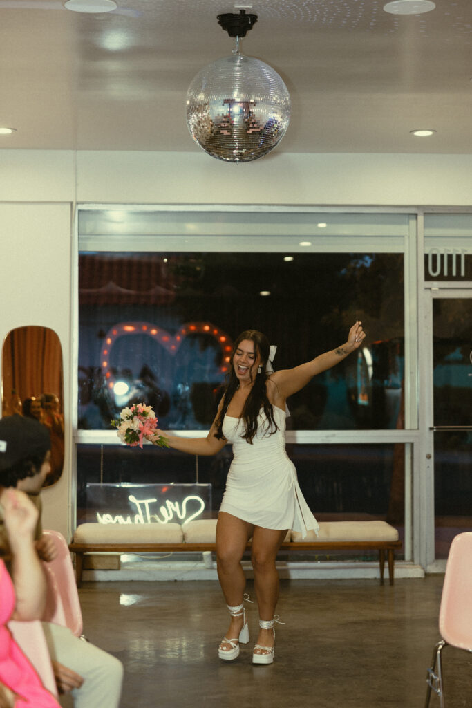a woman dances down the aisle under the disco ball at a vegas wedding chapel during wedding photos in vegas