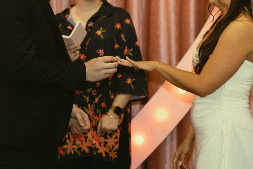 a man puts a ring on his wife's finger during their elopement wedding photos in vegas
