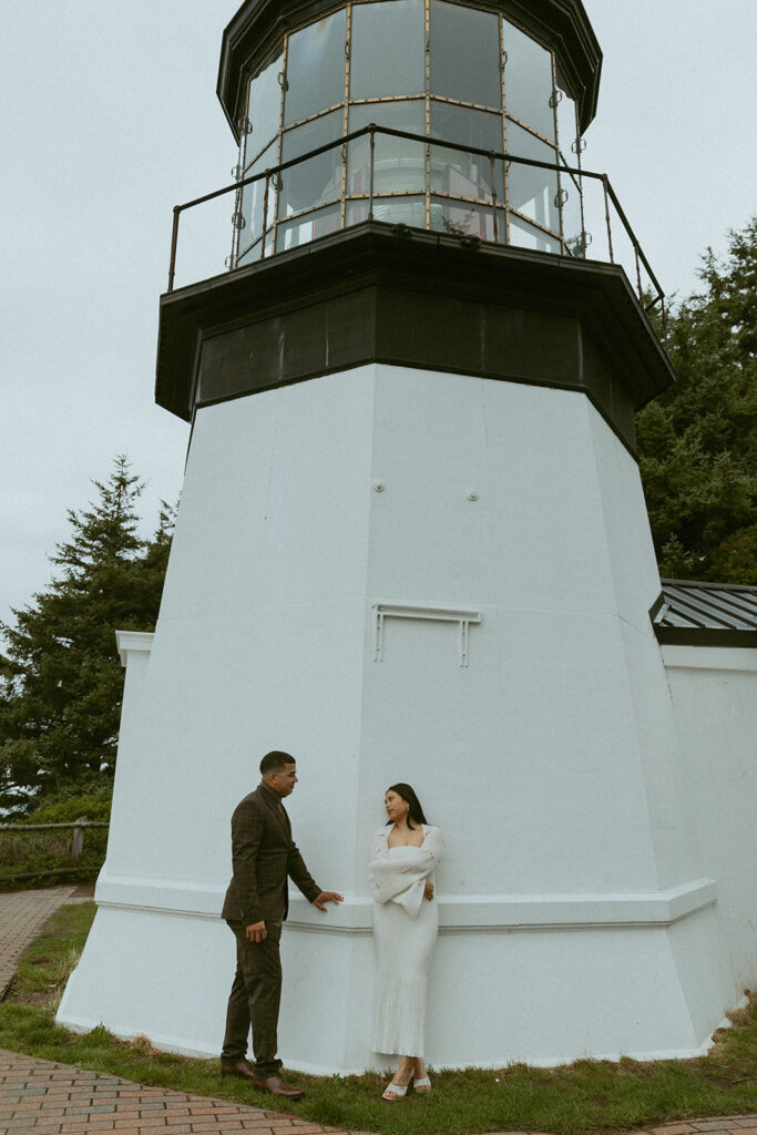 a could look at each other while leaning against a lighthouse during their elopement photoshoot