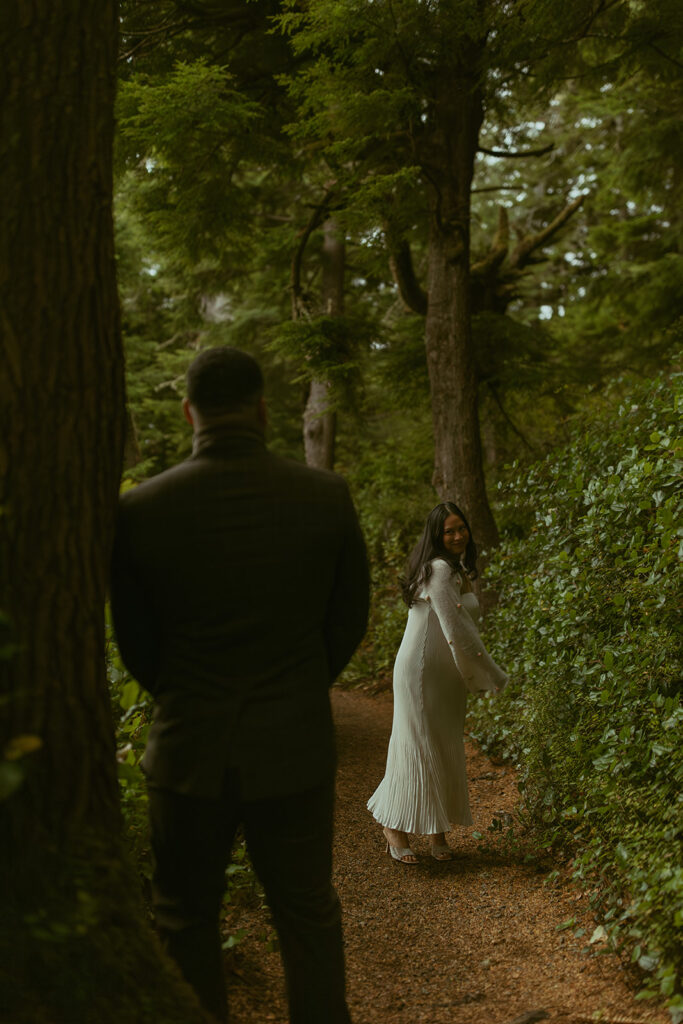 a woman sways while standing in the forest with her husband who faces her in the foreground