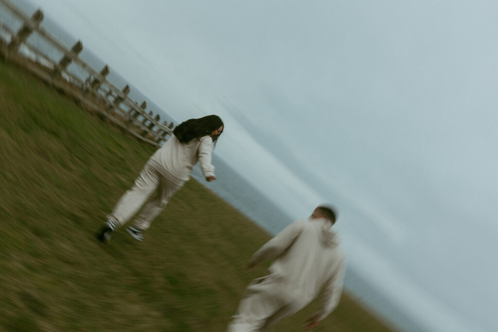 a motion blur portrait featuring a couple running toward the beach in matching sweatsuits