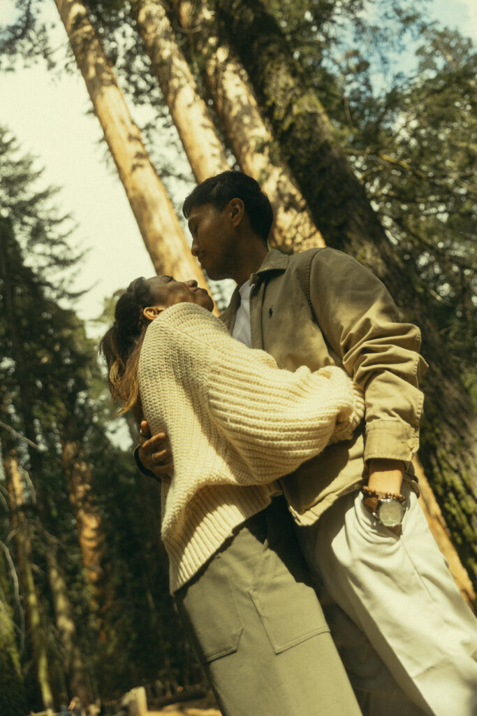 an engaged couple shares an embrace amongst the trees and shadows of sequoia national park