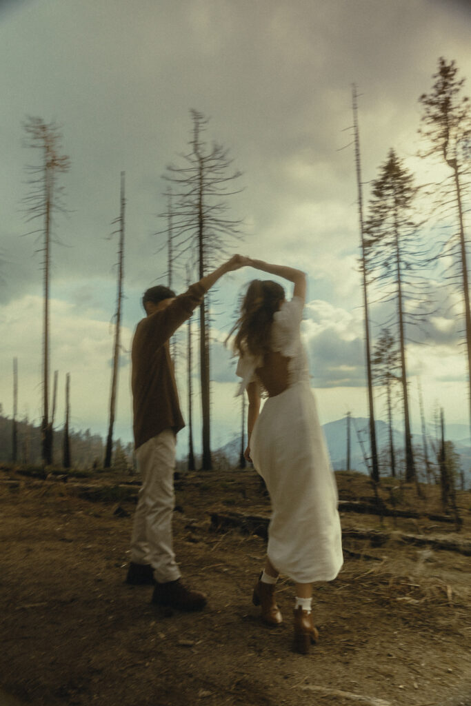 motion blur engagement photo at sequoia national park where the couple dances together in front of a blue sky with lots of clouds