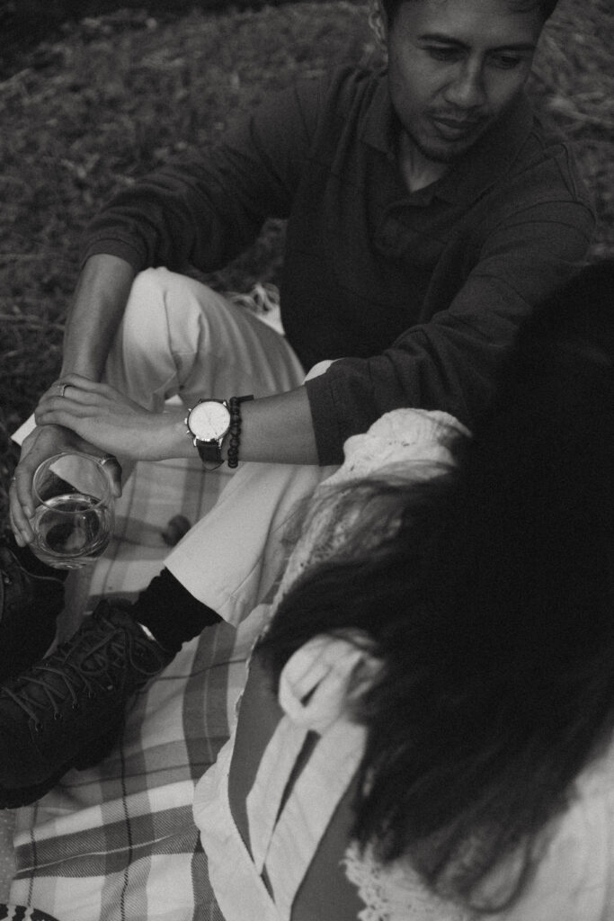 a cropped photo of a couple facing each other while sitting on a plaid blanket