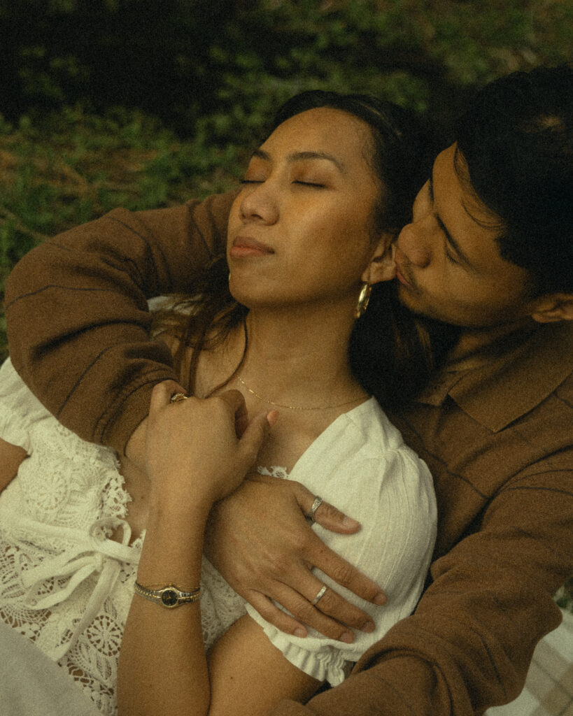 a woman lays in her fiancee's arms during their engagement photos