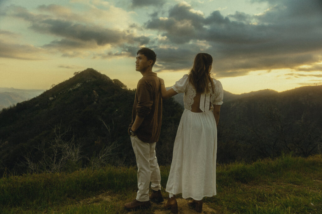 sequoia national park engagement photos where the couple stand in front of a cliff with mountains and the setting in the background