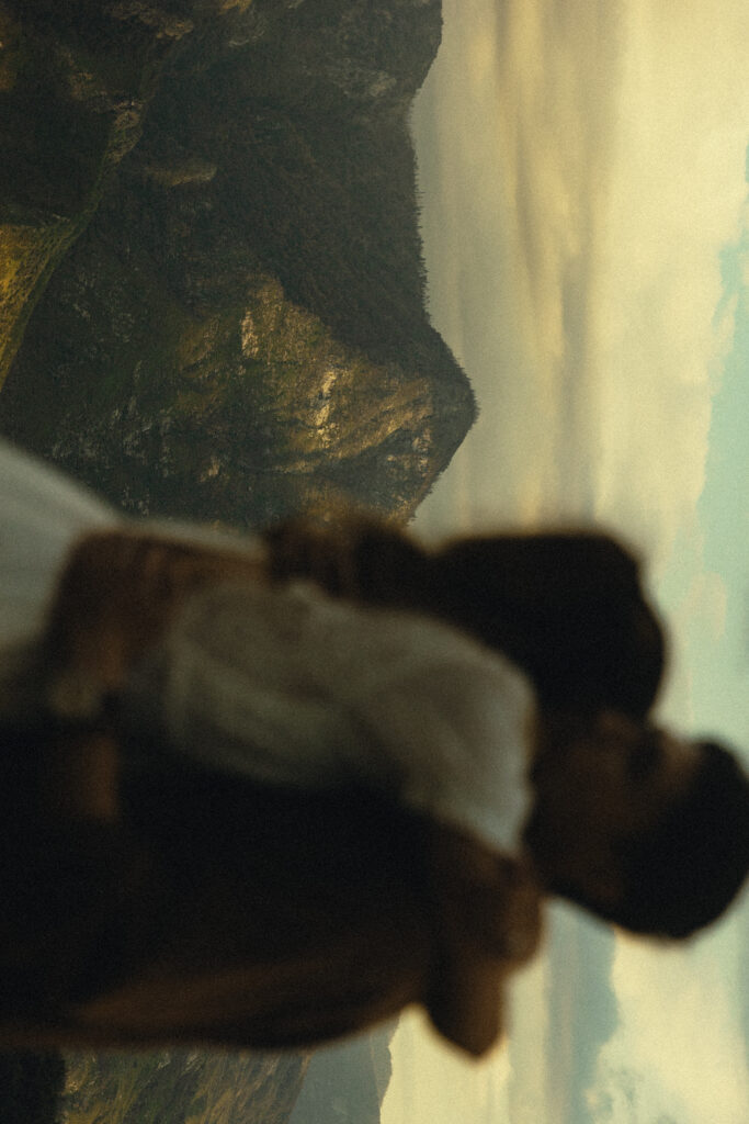 sequoia national park engagement photos where a couple shares a hug out of focus in the foreground with mountains and a soft sky behind them