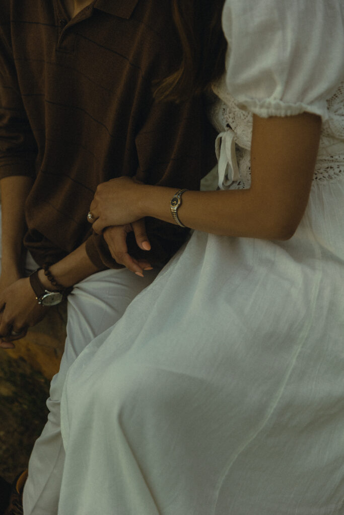 a cropped photo of a couple leaning against each other, her arm tucked in his