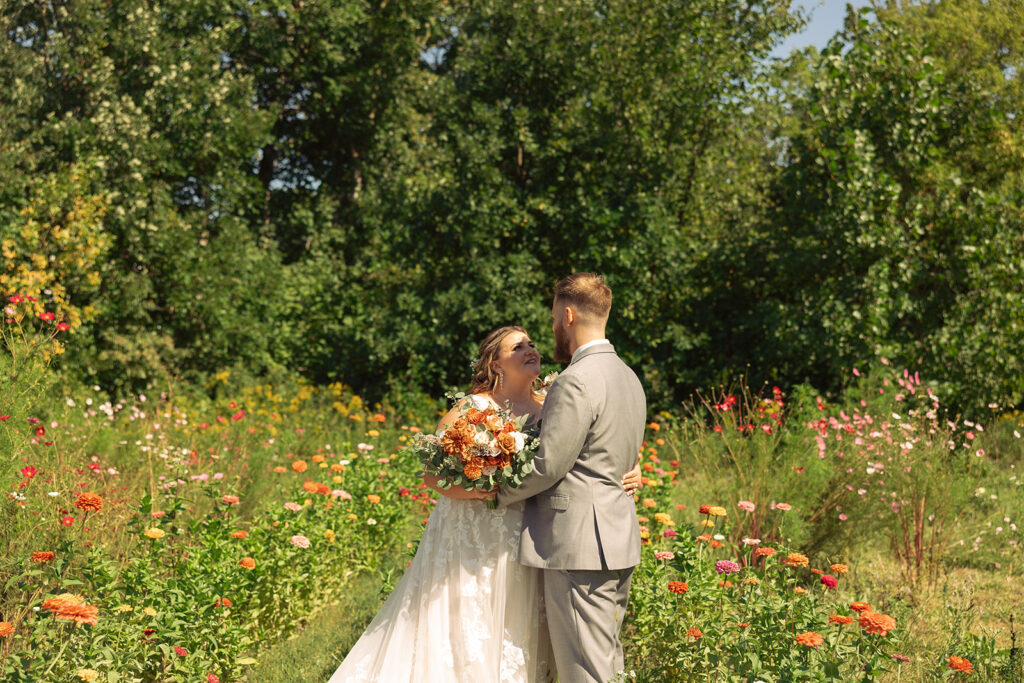Newlyweds embrace in a field of colorful flowers at one of the stunning venues in grand rapids michigan following their ceremony