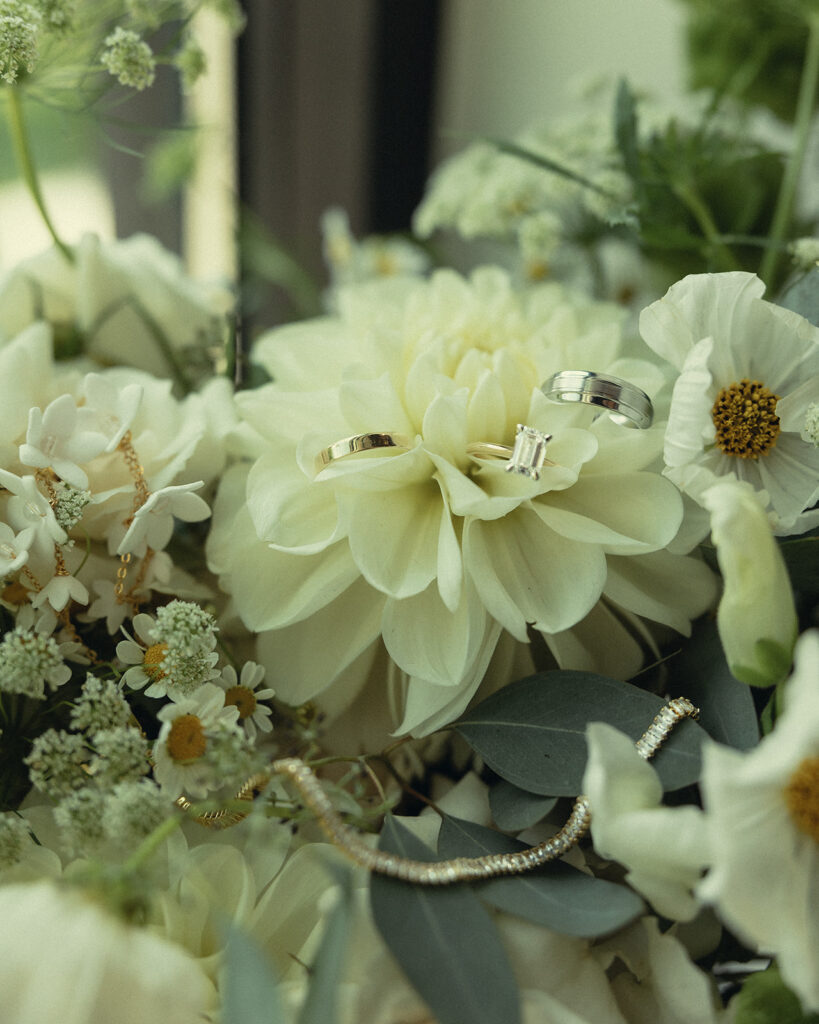A close up shot of a bridal bouquet with wedding rings nestled into the petals is shown at a small wedding venues in grand rapids mi
