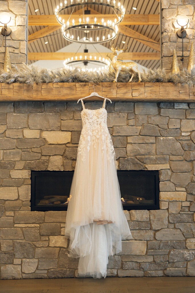A wedding gown is photographed against a rock fireplace at one of rustic wedding venues grand rapids mi