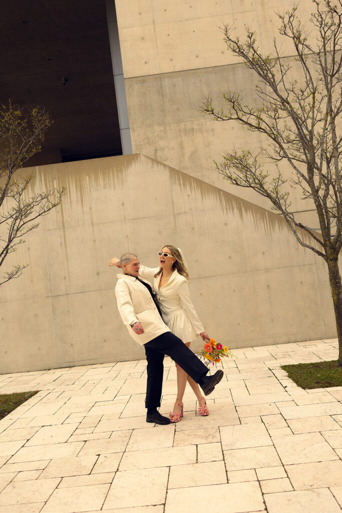 Newlyweds smile in a candid photo outside GRAM taken by Michigan elopement photographer, Anika B Photography