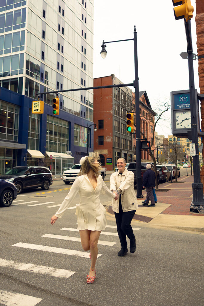 Newlyweds run hand-in-hand through a crosswalk in their wedding attire before their Kent Co. civil ceremony