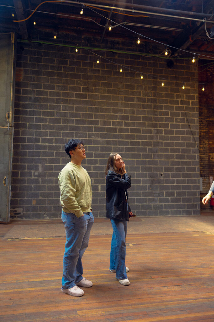 A Michigan couple stands underneath string lights at The Jam Handy Detroit while touring the MI venue 