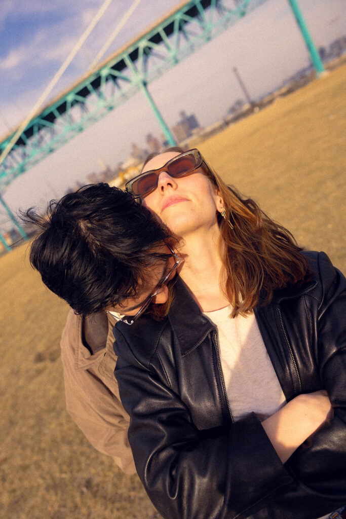 A Michigan couple embraces near the RiverWalk during their photoshoot with Detroit engagement photographer 