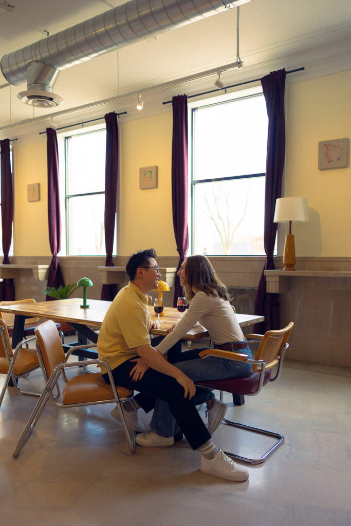A newly engaged couple enjoy glasses of wine during their Detroit engagement photos at Vespers Books and Wine 
