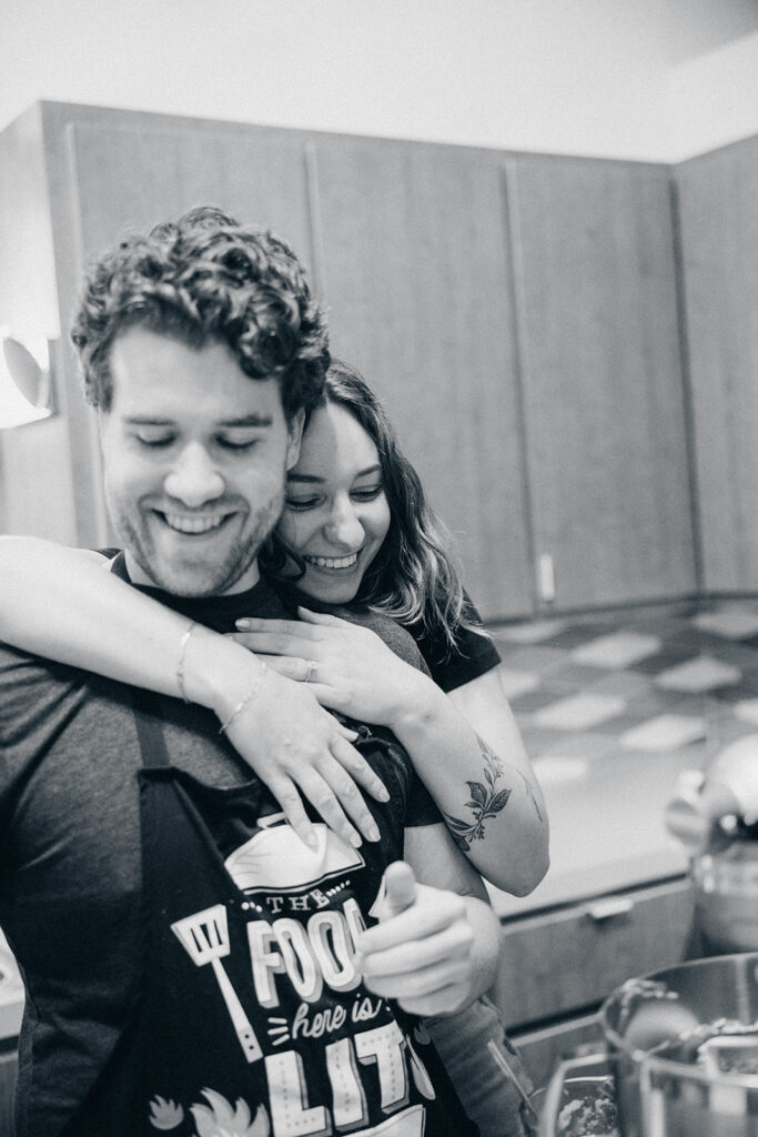 a b+w image of a MI couple hugging in their midcentury modern kitchen during their grand rapids engagement photos 