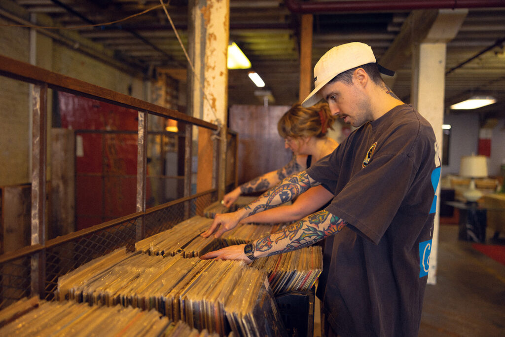 A couple browse the vinyl album stacks at Lost & Found, a local antique store, during Michigan engagement photos