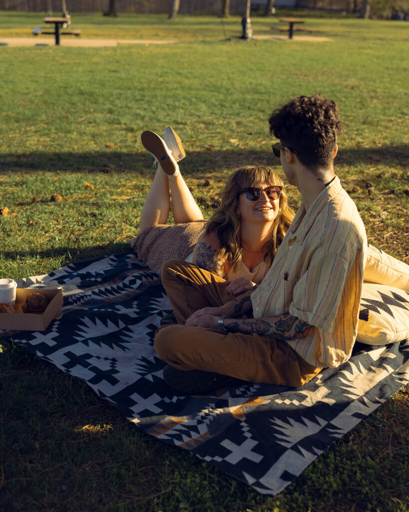 A couple relaxes on a blanket at Lookout Park during a Michigan engagement photoshoot
