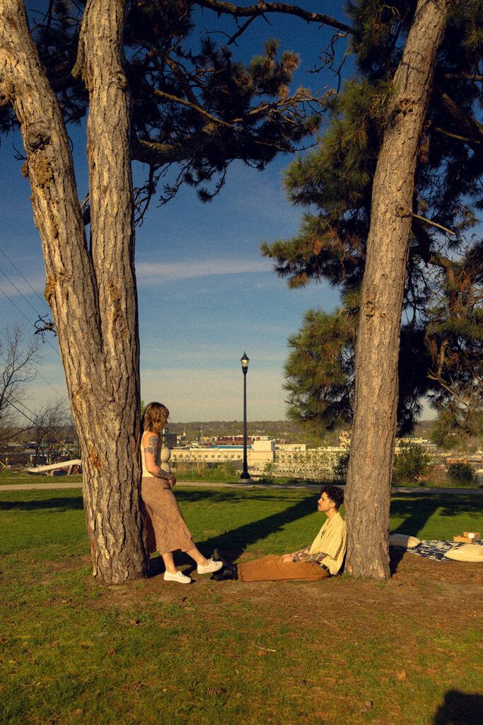A Grand Rapids couple lean against trees in Lookout Park during Michigan engagement photos