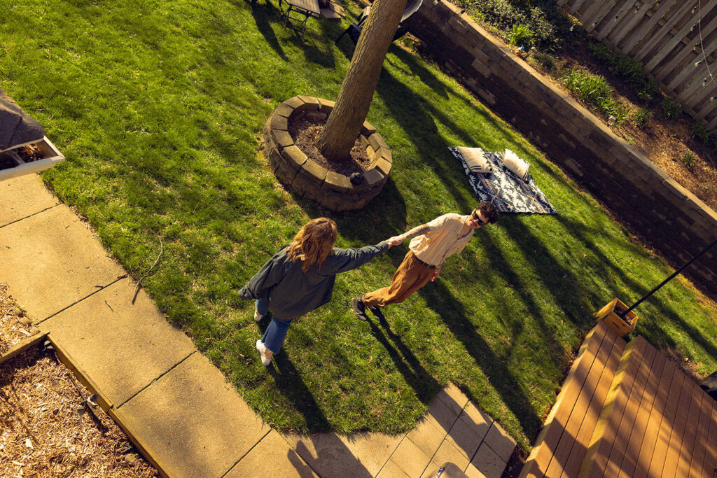 A Michigan couple holds hands in the back yard of their home during engagement photography Grand Rapids MI