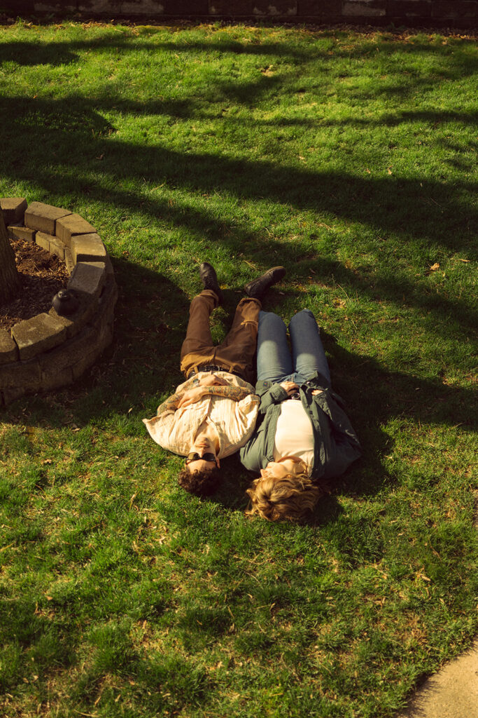 Michigan engagement photo shows a couple lying in the grass of their Grand Rapids back yard