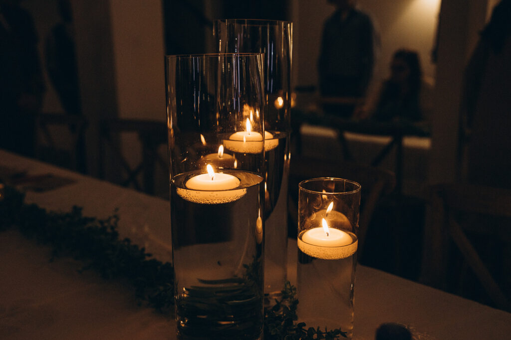 Table decor consisting of lit floating candles are photographed at a West Michigan wedding reception 