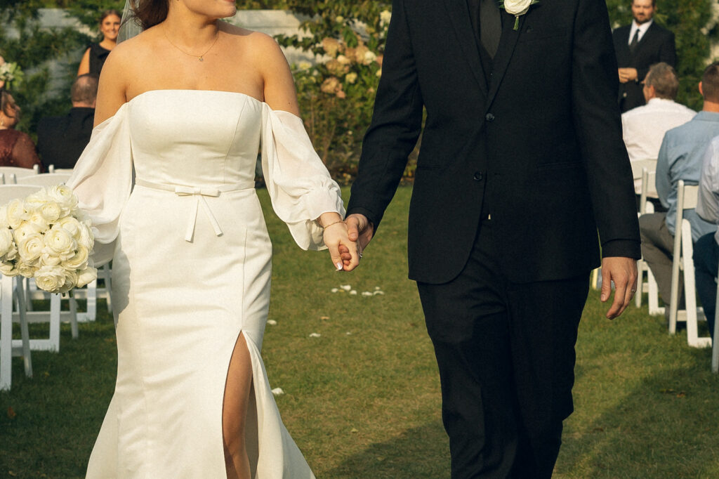 Newlyweds walk hand-in-hand down the aisle in a photo taken by Michigan wedding photographer, Anika B Photography