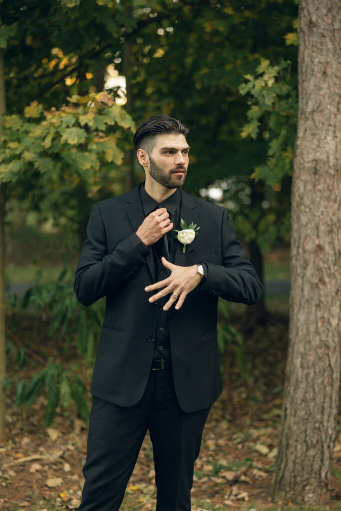A groom wearing all black shows off his new gold wedding band in a photo taken at one of the upper peninsula michigan wedding venues