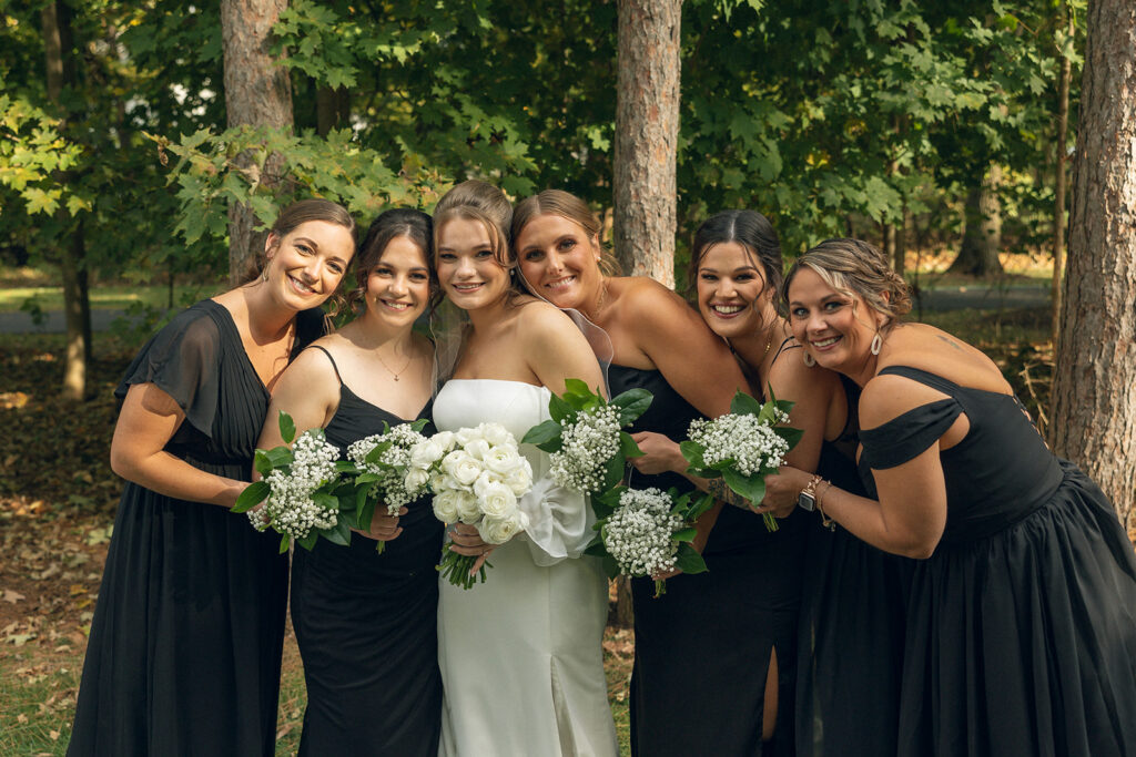 A MI bride poses with her wedding party following her ceremony at an outdoor wedding venue in west MI
