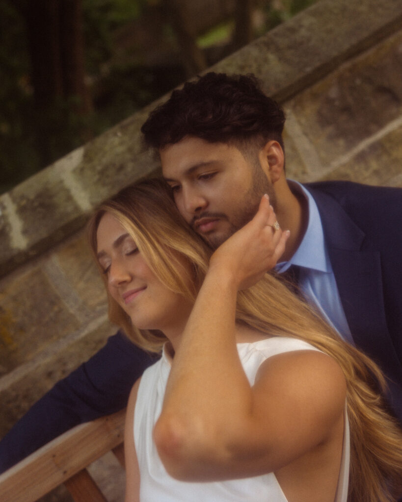 A close-up photo depicts a young blonde woman leaning against her soon-to-be husband during an engagement session at the Ford Mansion in Grosse Pointe 