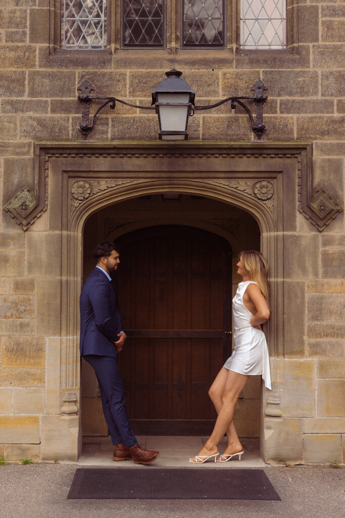 An engaged couple lean against opposite sides of an entry way at Ford House in Grosse Pointe MI during an engagement photoshoot