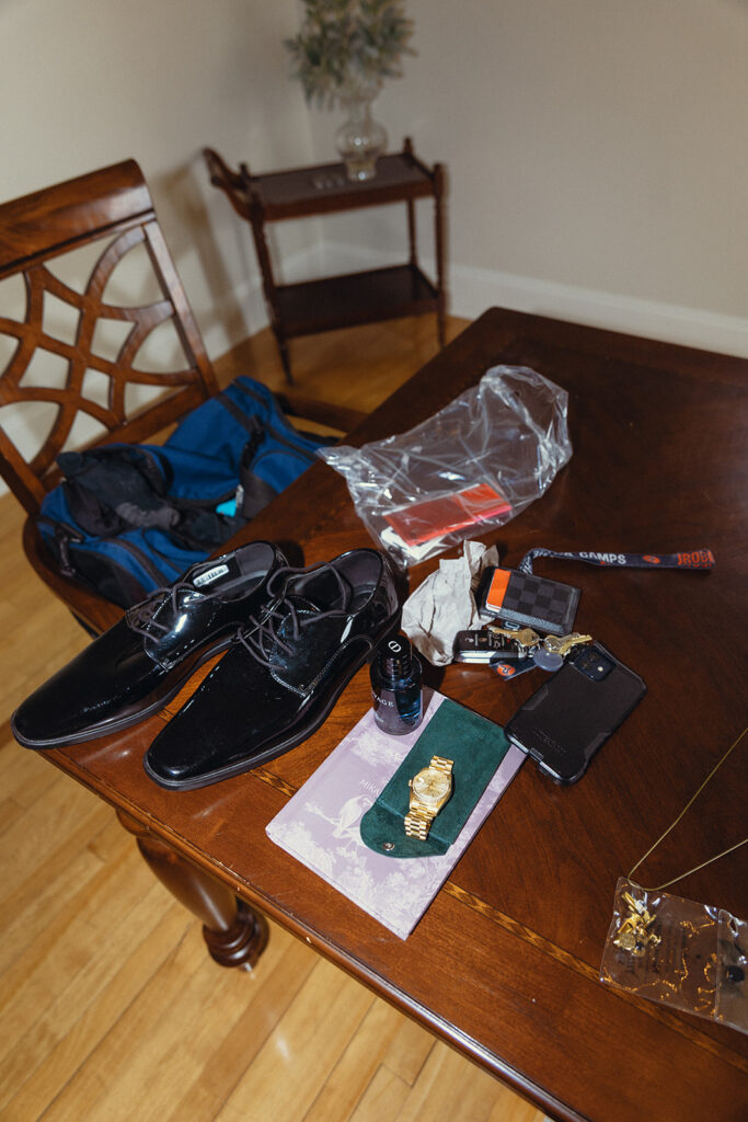 A wedding detail photo showcases a groom's shoes, watch, and accessories in an editorial shot taken at venue 3 two