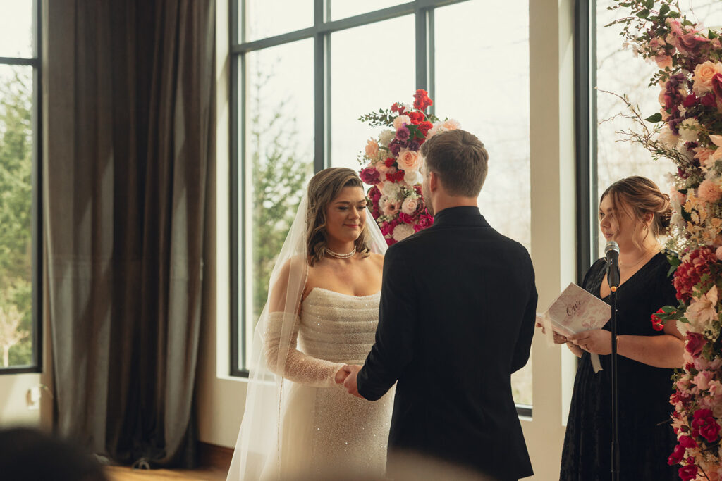 A bride & groom hold hands at the altar of their wedding held at Venue3TWo